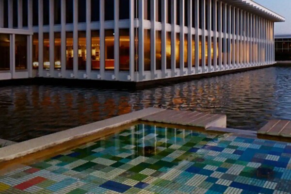 Two people sitting on sofas in a waiting room with wall clocks behind them