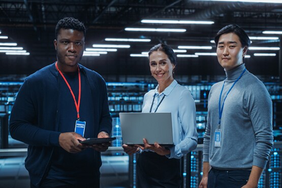 Three colleagues holding laptop and smiling
