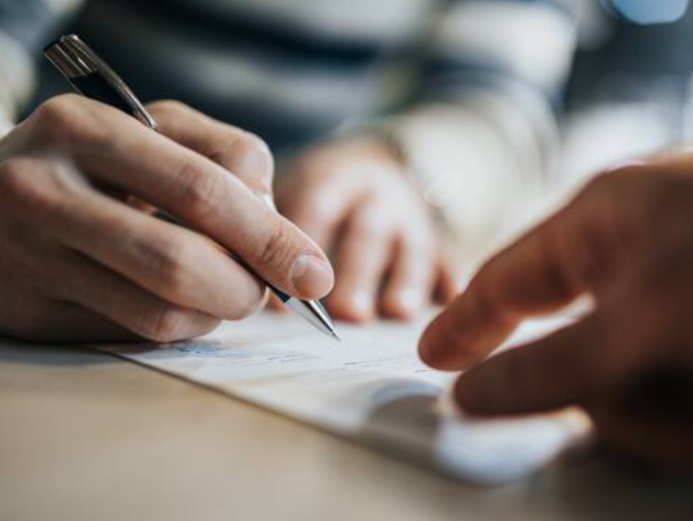 Close-up of a person signing a document with a pen