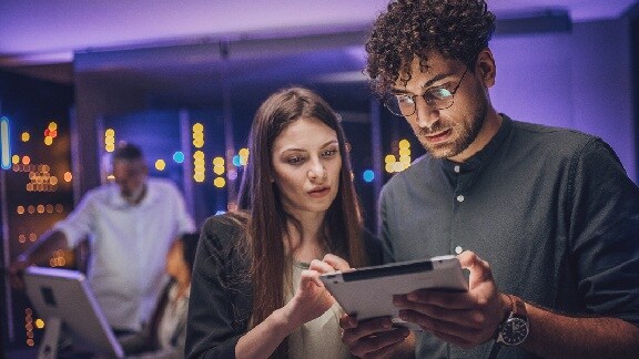 Two colleagues discussing work on a tablet in an office