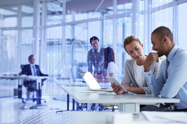 Two employees conversing sitting at a table in an office with modern graphics