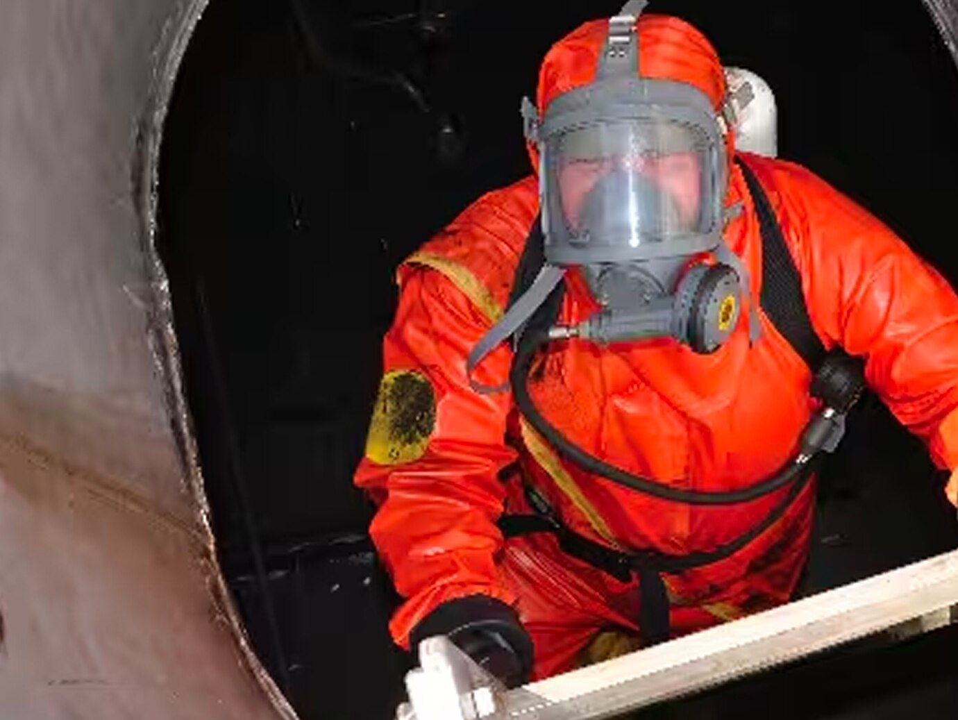 Firefighter in safety gear climbing out of a confined space