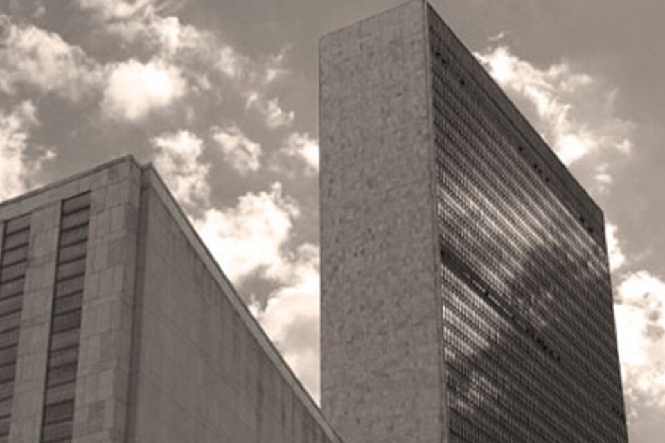 A greyscale image of the United Nations building in New York City against the sky