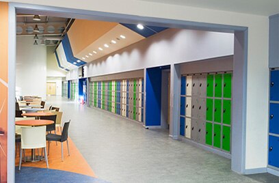 A school hallway with lockers and circular tables with chairs