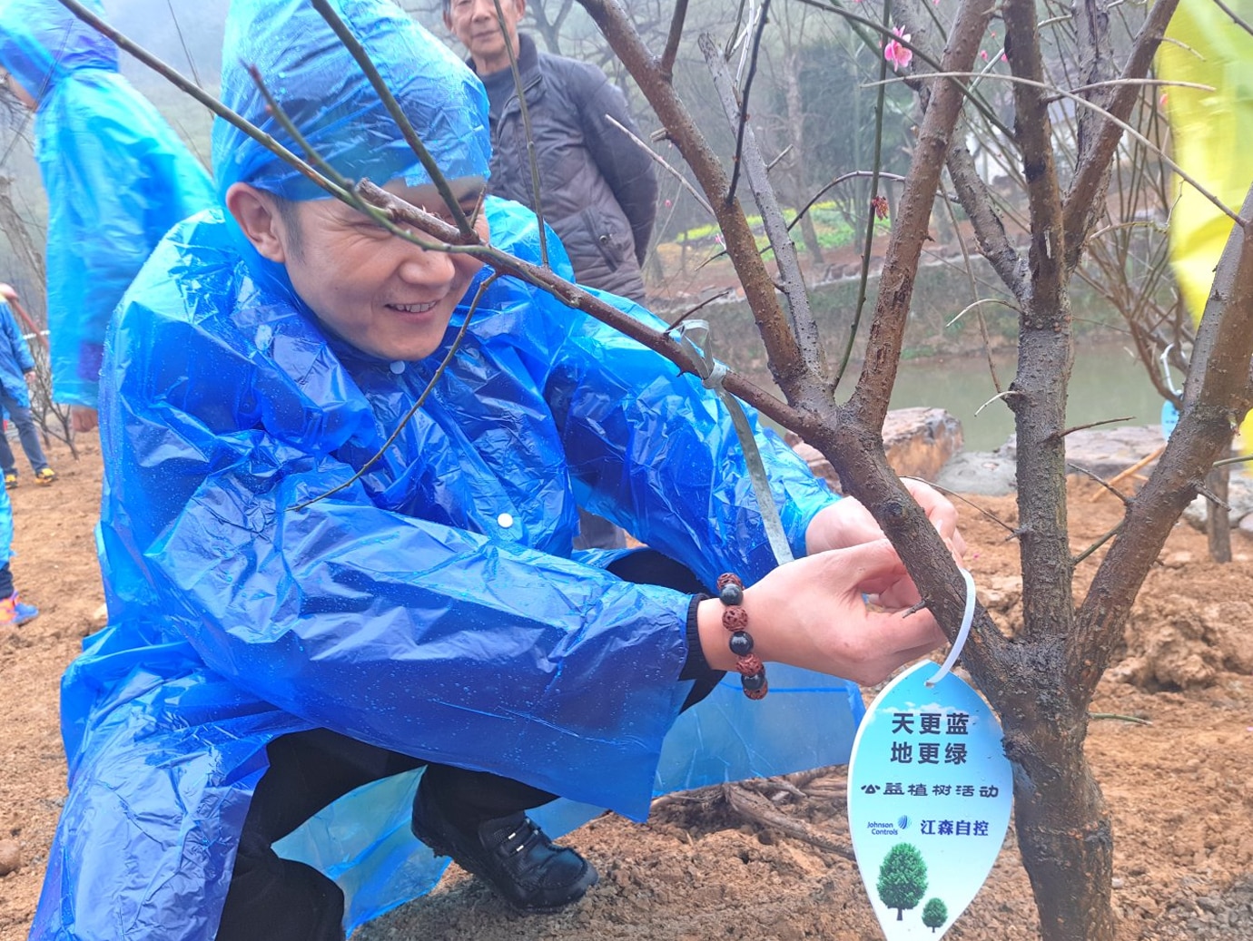 Man in raincoat tying a tag to a plant to promote sustainability