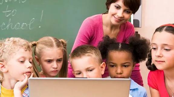Teacher and kids using a desktop in a classroom