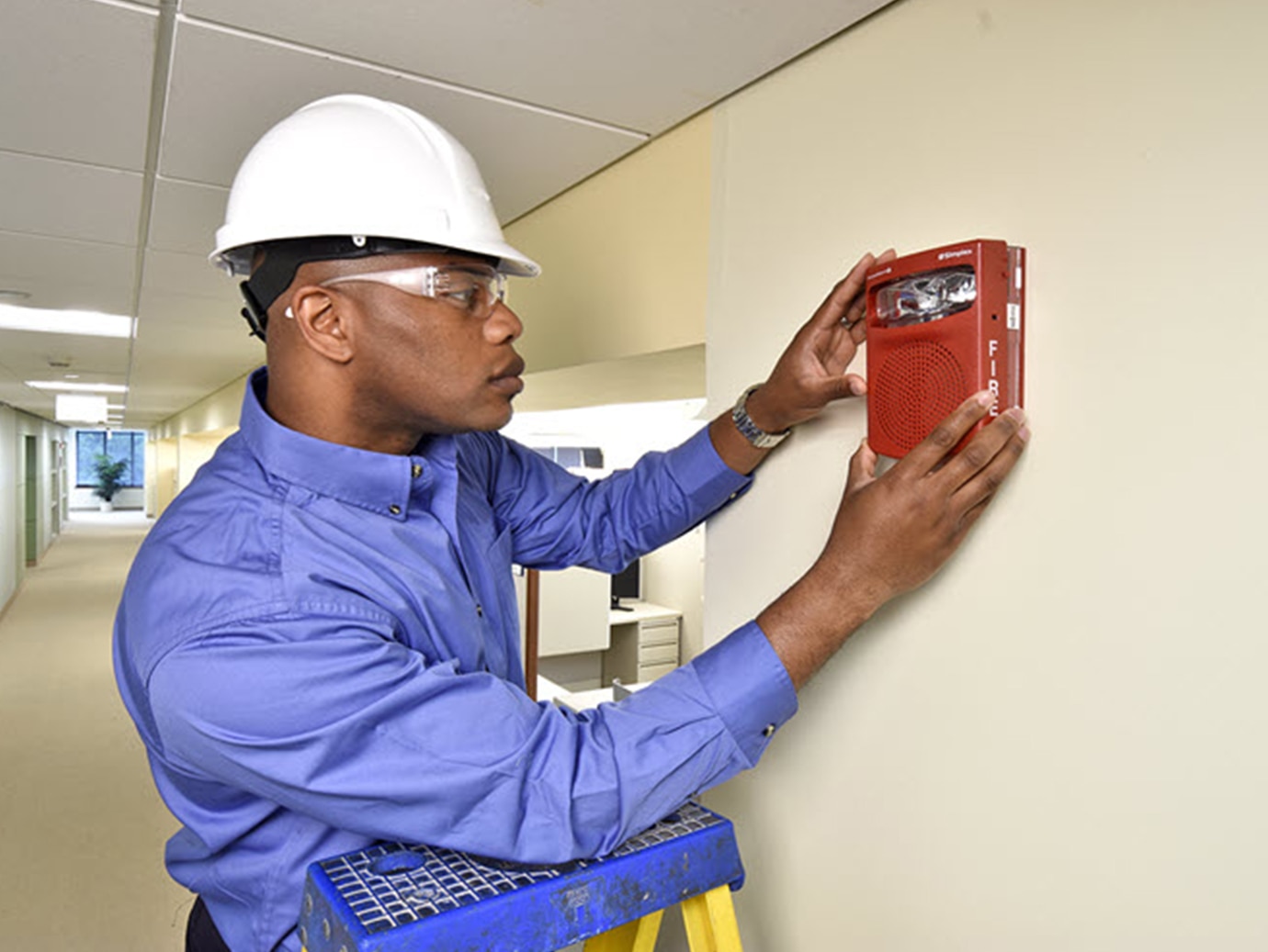A person wearing a hard hat and holding a red speaker