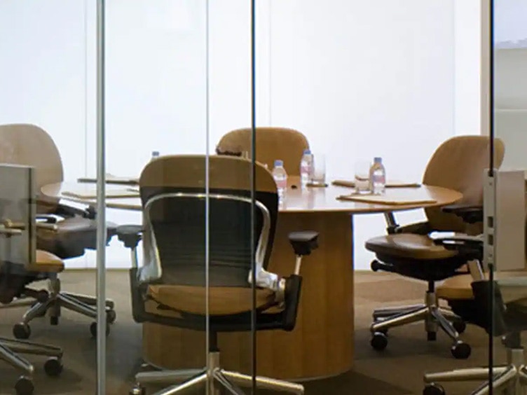A conference room with glass walls next to a corridor