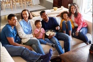 Family sitting on a couch with one person holding a bowl of popcorn