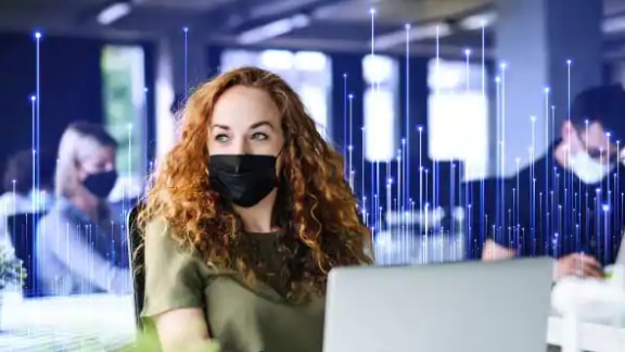 Woman in face mask working at her desk in office