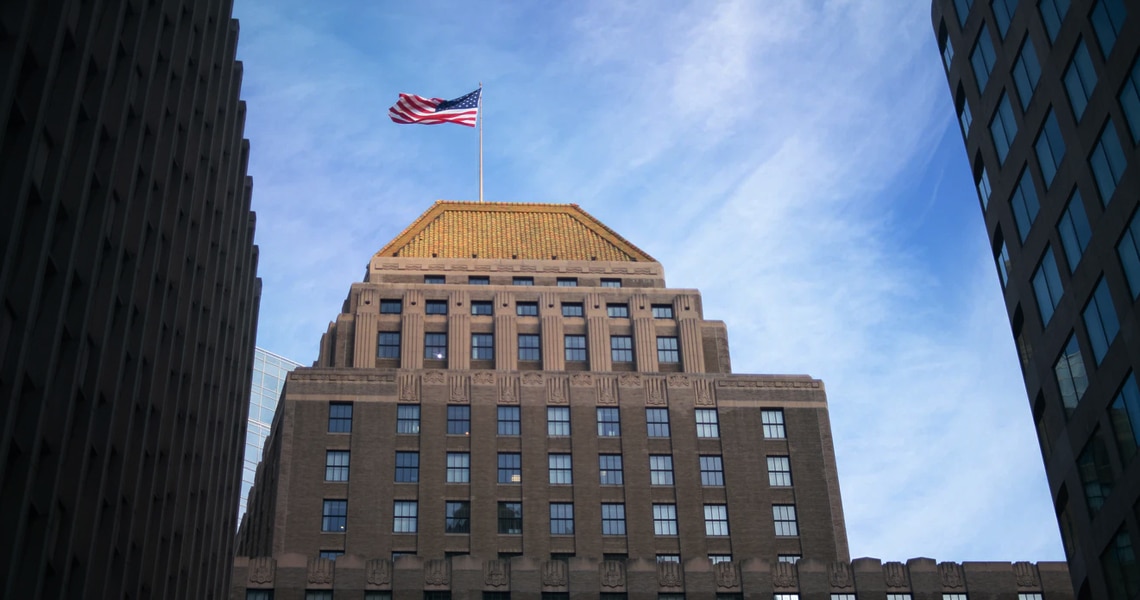 A brown concrete building, with the American flag flying on top, in downtown Boston