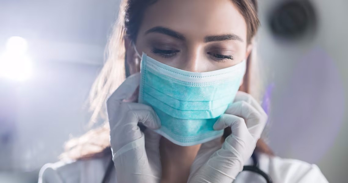 A female doctor putting on a facemask