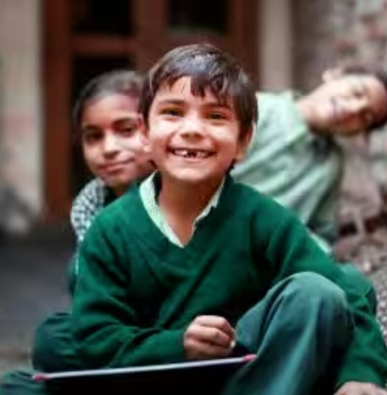 Young children at a school in rural India, holding slates and smiling