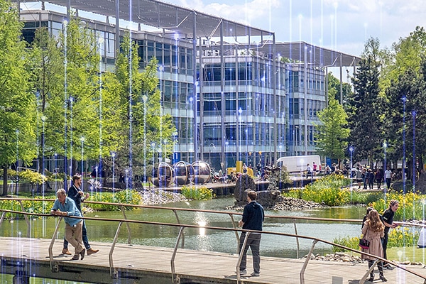 People walking along a bridge in a business park, with OpenBlue graphics overlaid in the background