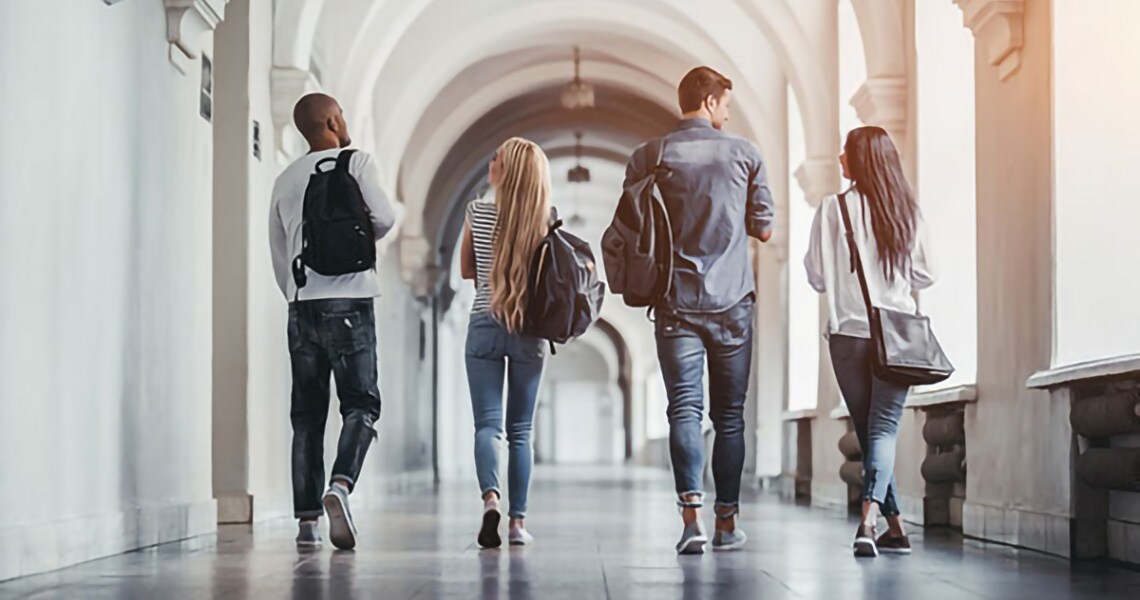 Rearview shot of group of students walking in university corridor