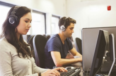 man and woman wearing headphones and working on computers