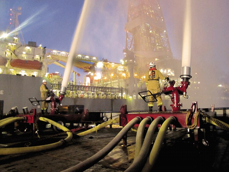 Firefighters operating water-based fire suppression equipment in an industrial area