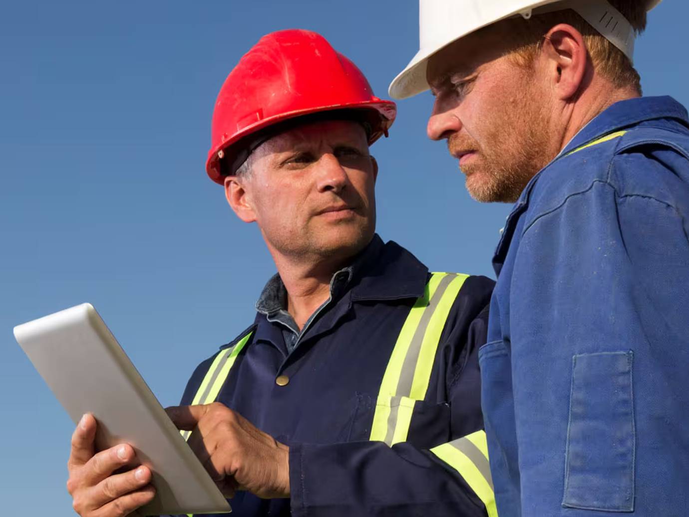 Two engineers discussing something, while one holds a tablet
