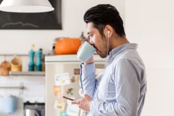 Man drinking from a mug leaning on a kitchen counter
