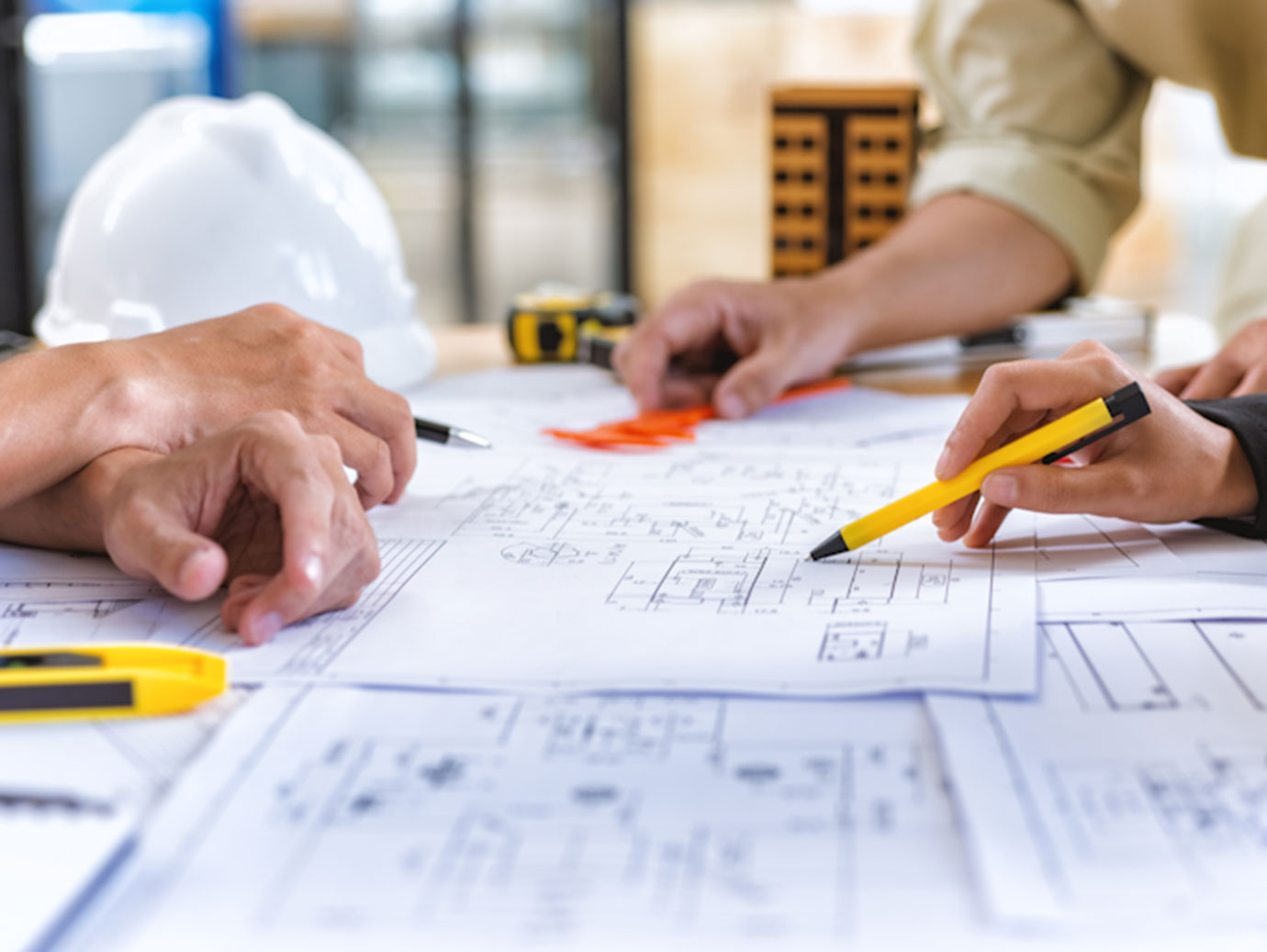 three people pointing at construction blueprint