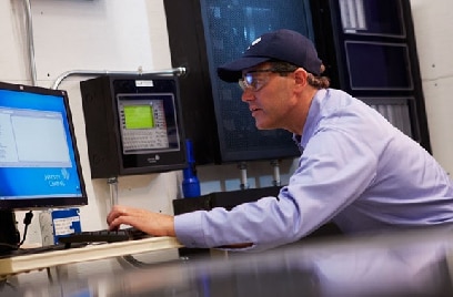 A man working at a desktop with a Johnson Controls wallpaper