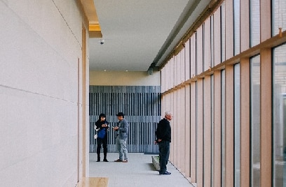 People standing in an office corridor with glass windows on one side