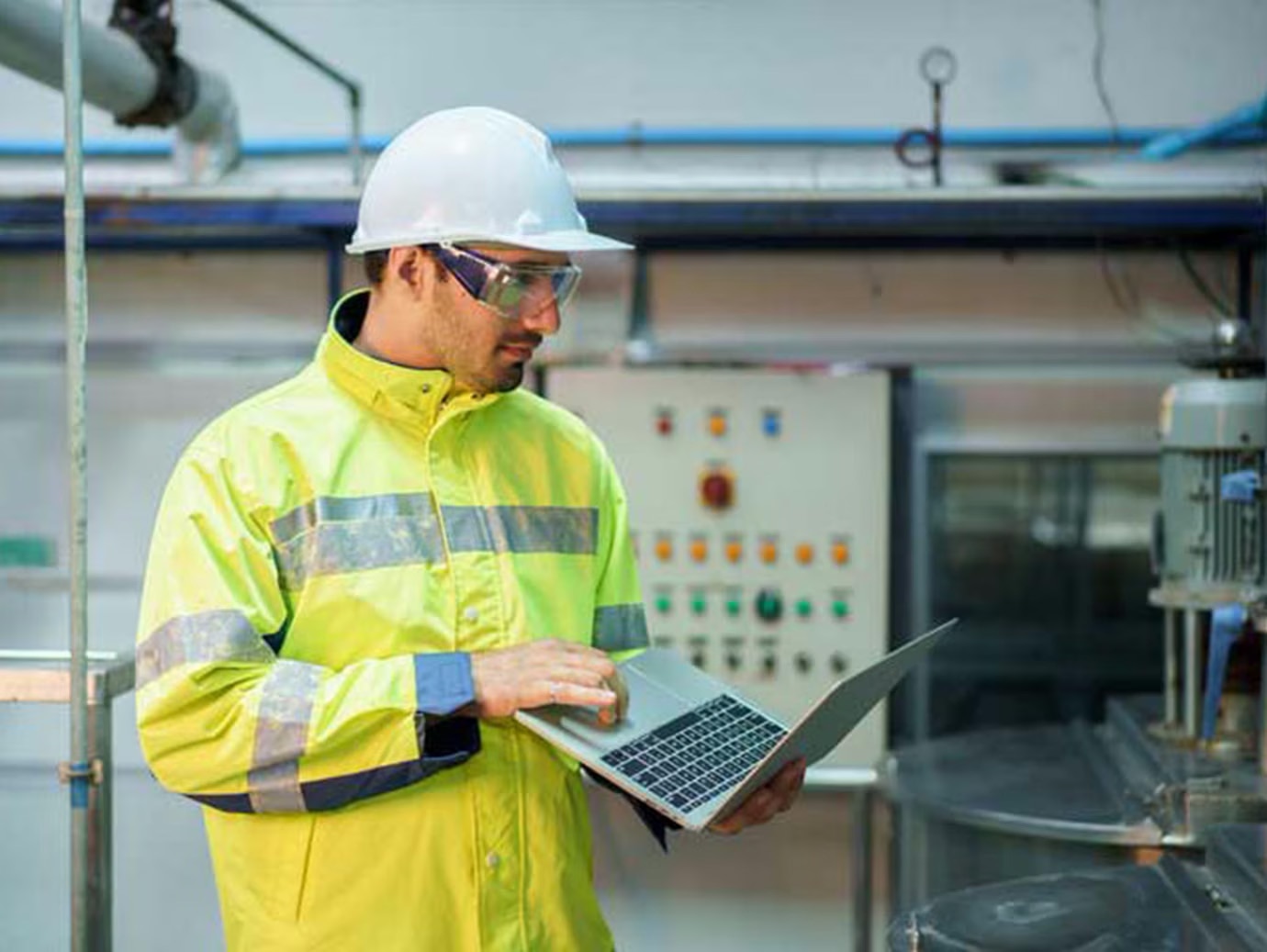 A mechanic in protective gear holding a laptop