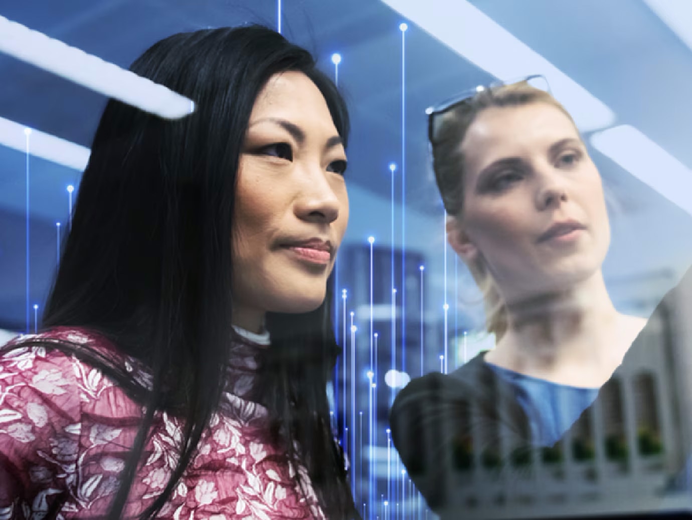 Two women looking into the distance as one of them points at something, overlaid with OpenBlue graphics