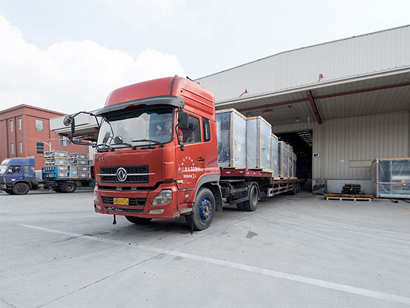 A truck carrying huge boxes of products leaving a building