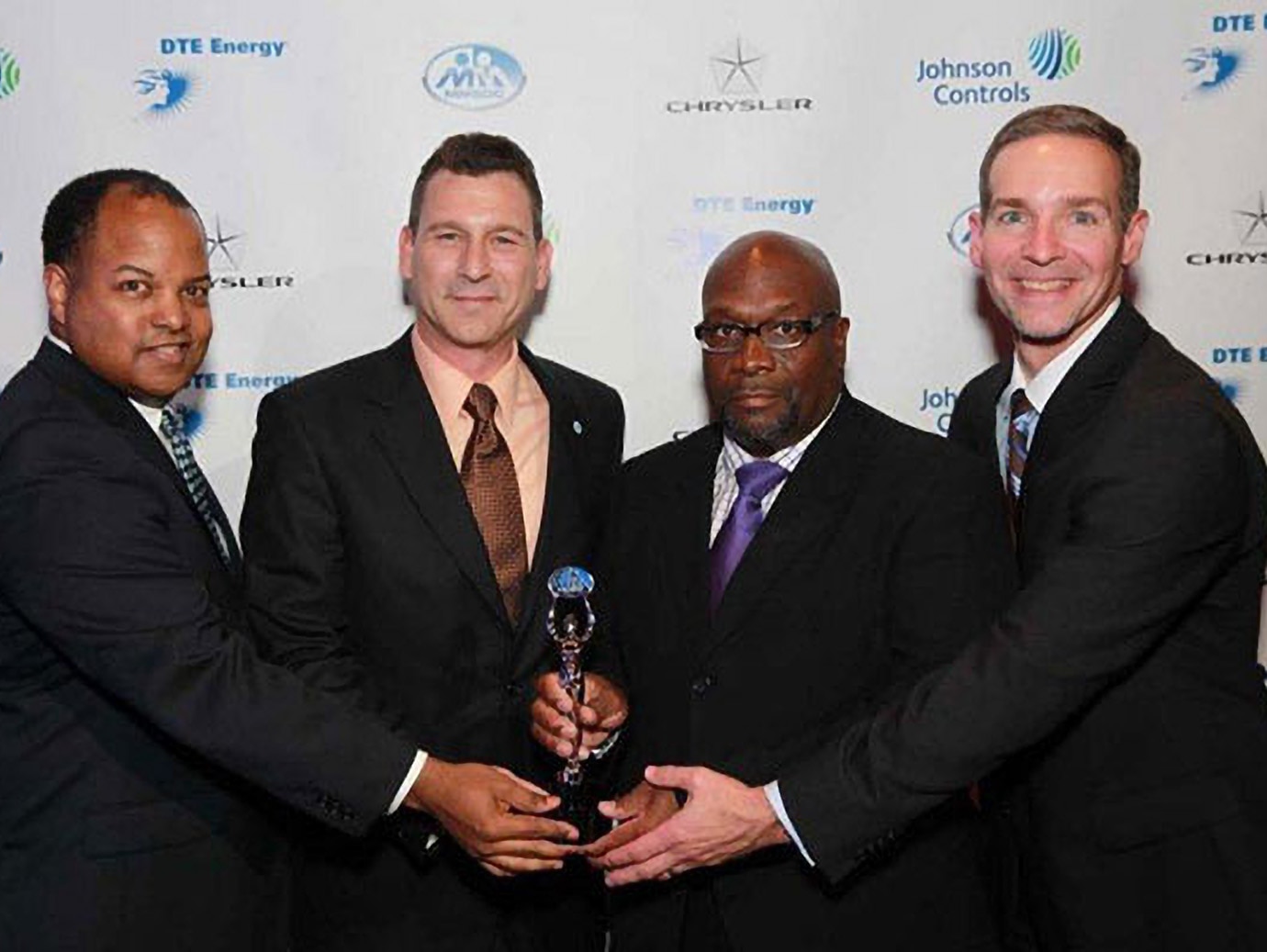 A group of four men holding an award and posing