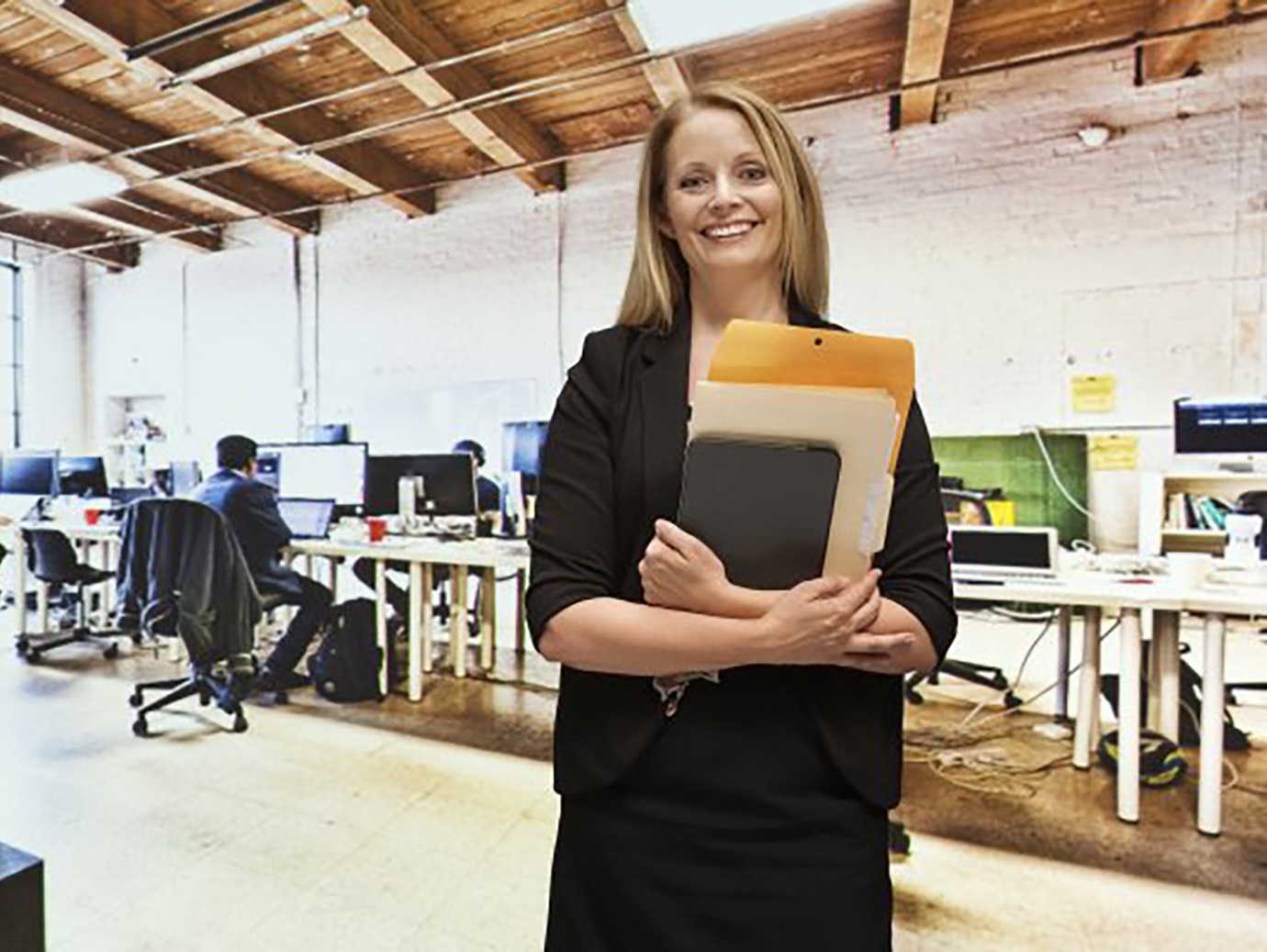 Woman standing in an office room with a set of files in her hand