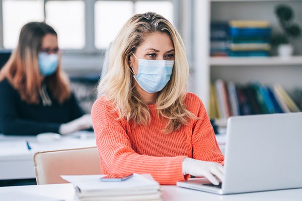 Women wearing a mask and work on laptop in library