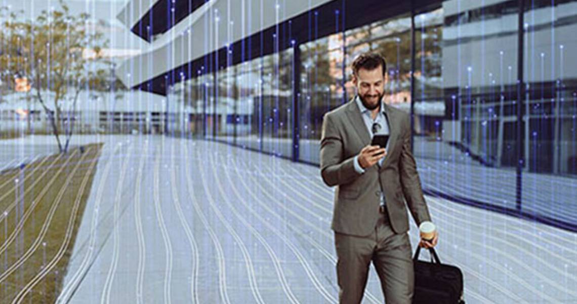 Male corporate worker walking in an office while looking at his phone